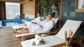 Un área de spa con tumbonas de madera, una piscina y una pared de vidrio con un letrero.