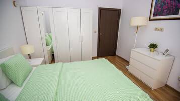 A bedroom with a bed, a dresser, a nightstand, a lamp, and a door.