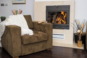 A brown sofa with a white throw blanket, a fireplace with a visible fire, and a small plant in a wooden pot. - The Balkan Jewel Resort, Trademark Collection By W (Razlog)