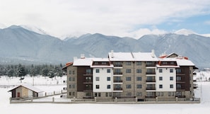 A multi-story hotel with balconies, a snow-covered landscape, and mountains in the background. - The Balkan Jewel Resort, Trademark Collection By W (Razlog)