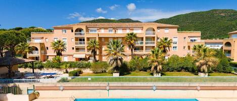 Un hôtel doté d’une piscine, de palmiers et surplombant un paysage montagneux.
