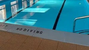 Una piscina interior con agua cristalina, paredes de madera y un cartel que indica 'NODIVING'.