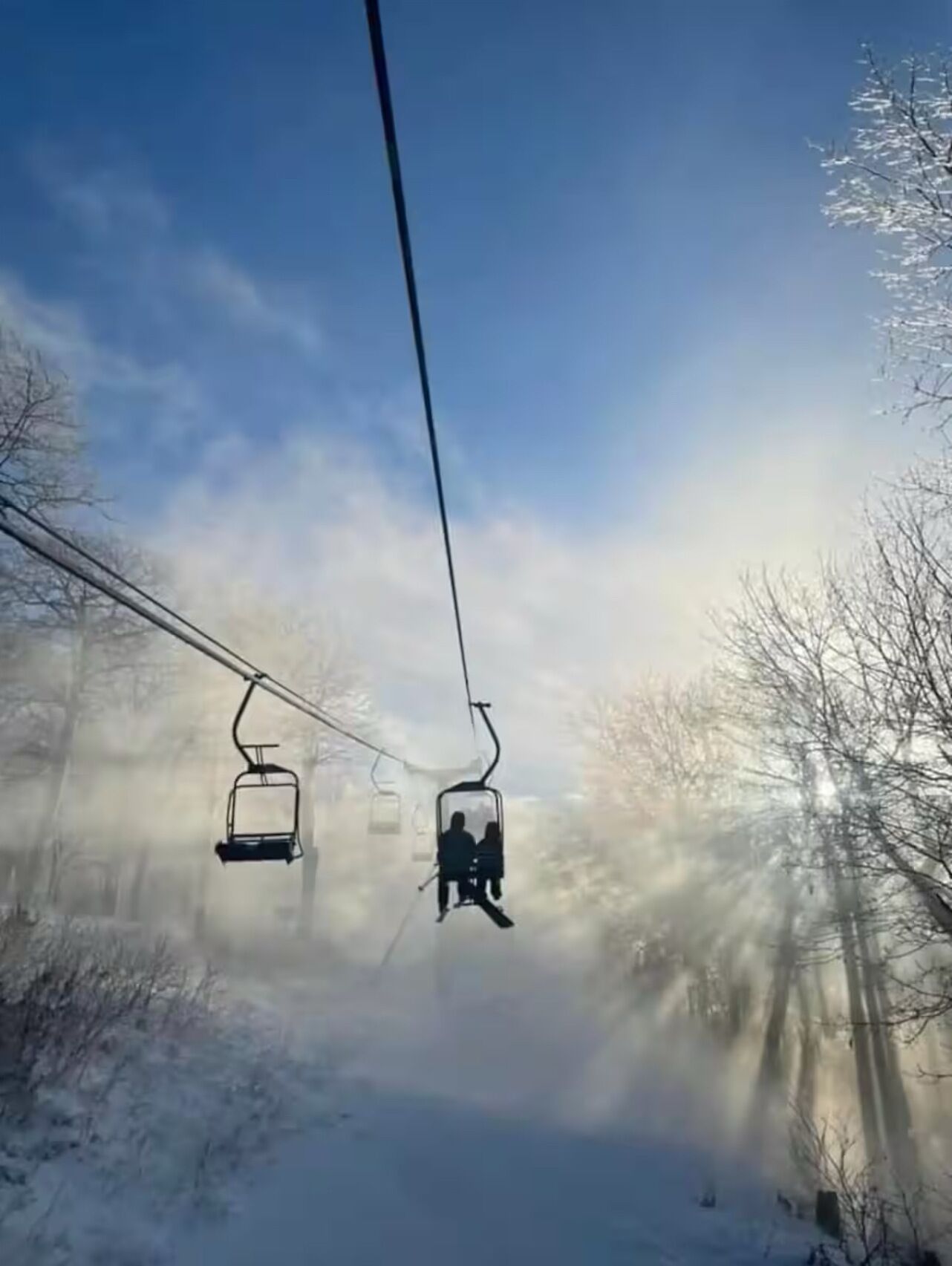 Een skilift in een besneeuwd landschap met heldere lucht.