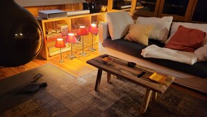 Un salon chaleureux avec une table basse en bois, un canapé agrémenté de coussins et un lampadaire doté de plusieurs lampes.