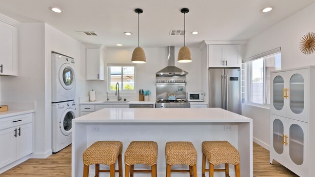 Een moderne keuken met een centraal eiland, inbouwapparatuur en een groot raam.