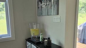 Una habitación con una consola negra, un cuadro, una ventana y una puerta que da al exterior.