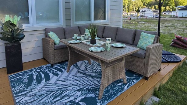 Una terraza con un sofá de mimbre, una mesa y una sombrilla.