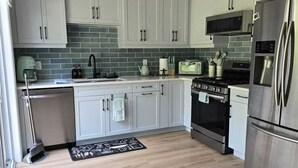 Una cocina moderna con armarios blancos, un refrigerador de acero inoxidable, un microondas y una estufa.