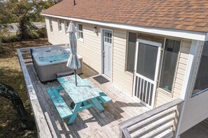 A backyard with a hot tub, a picnic table, and a covered umbrella.