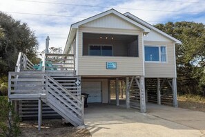 A two-story building with a covered entrance and a staircase leading up to a dock. - Oceanside - Dog Friendly - Hot Tub (Kill Devil Hills)