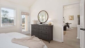 Un dormitorio con cama, cómoda, espejo y puerta que da a un balcón.