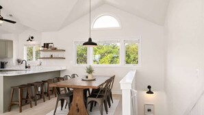 Una cocina luminosa con una isla grande, sillas de madera y una mesa de comedor.