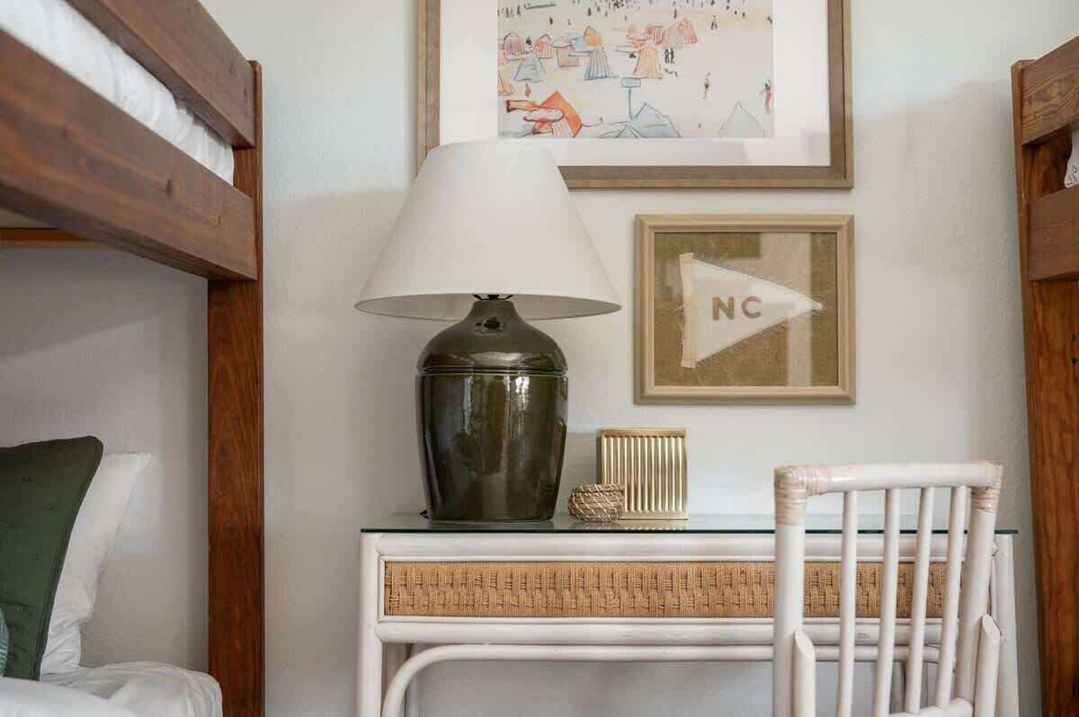Une chambre avec un lit superposé, un bureau avec une lampe, une chaise et des œuvres d’art encadrées accrochées au mur.