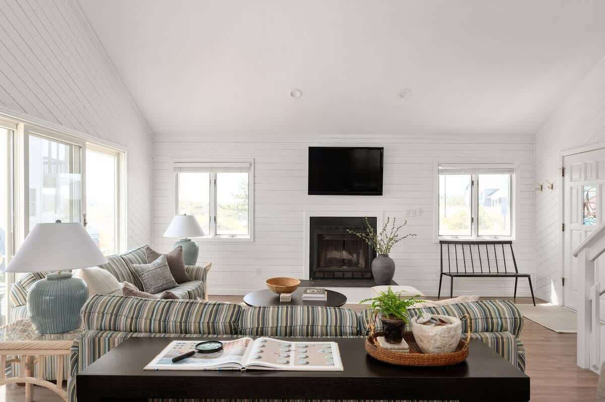 Een moderne woonkamer met gestreepte banken, een open haard en een flatscreen televisie.