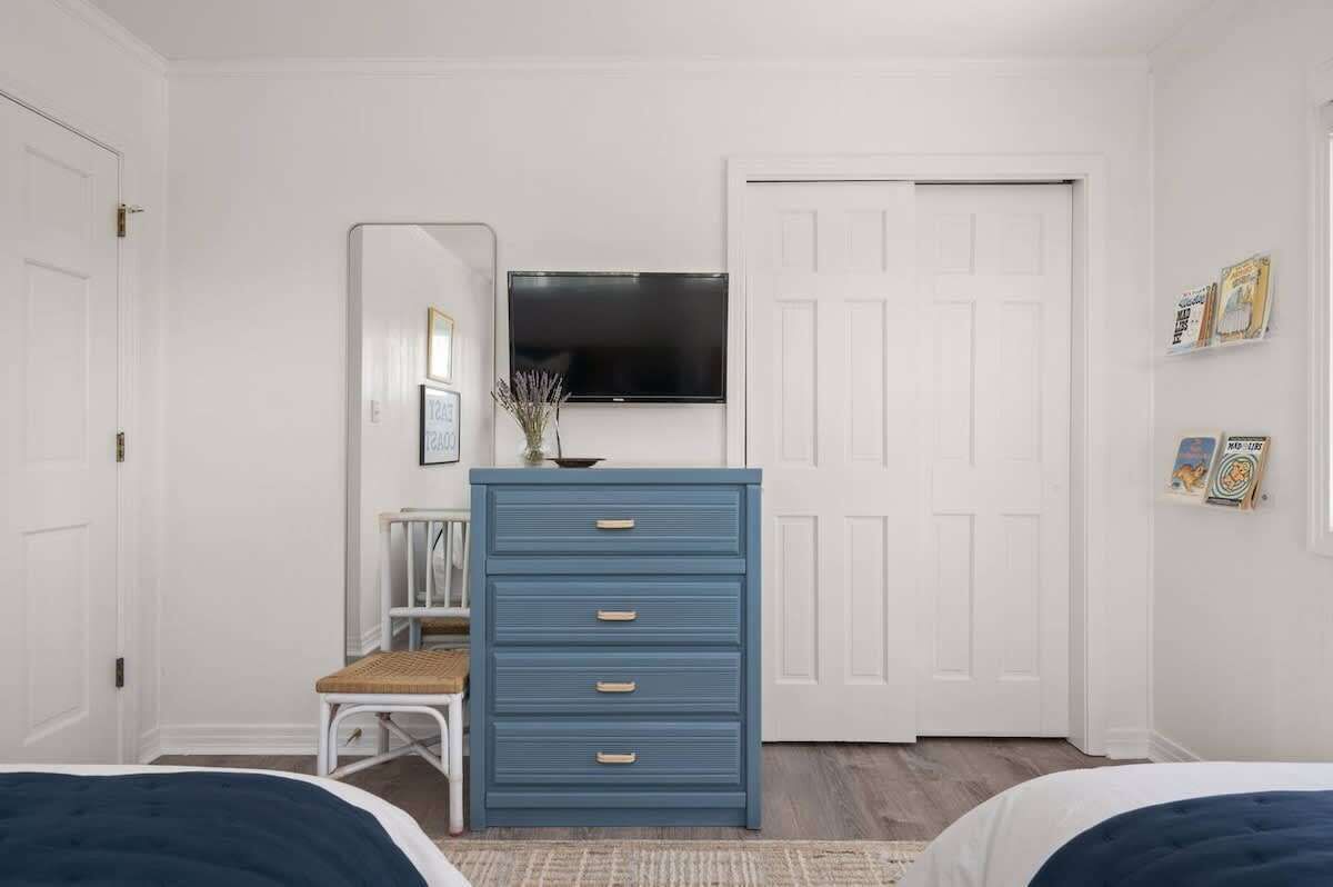 Een slaapkamer met een bed, een kaptafel, een stoel, een televisie en een deur.