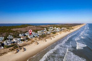 A coastal residential area with houses along the beach, a clear sky, and a view of the ocean. - Oceanfront, Pool & Hot Tub, Game Room, EV Charger (Corolla)