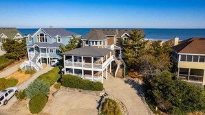 A coastal residential area with multiple two-story houses featuring balconies, a clear view of the ocean, and a well-maintained landscape. - Oceanfront, Pool & Hot Tub, Game Room, EV Charger (Corolla)