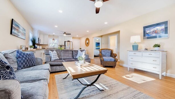 A spacious living room with a sofa, coffee table, and a dining area. - Cozy Soundside Cottage  • Bring Your Dog! (Kill Devil Hills)