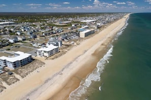 An aerial view of a coastal town with a long beach, residential buildings, and a clear sky. - Heated Pool, Hot Tub, 4Min Walk to Beach (Kill Devil Hills)