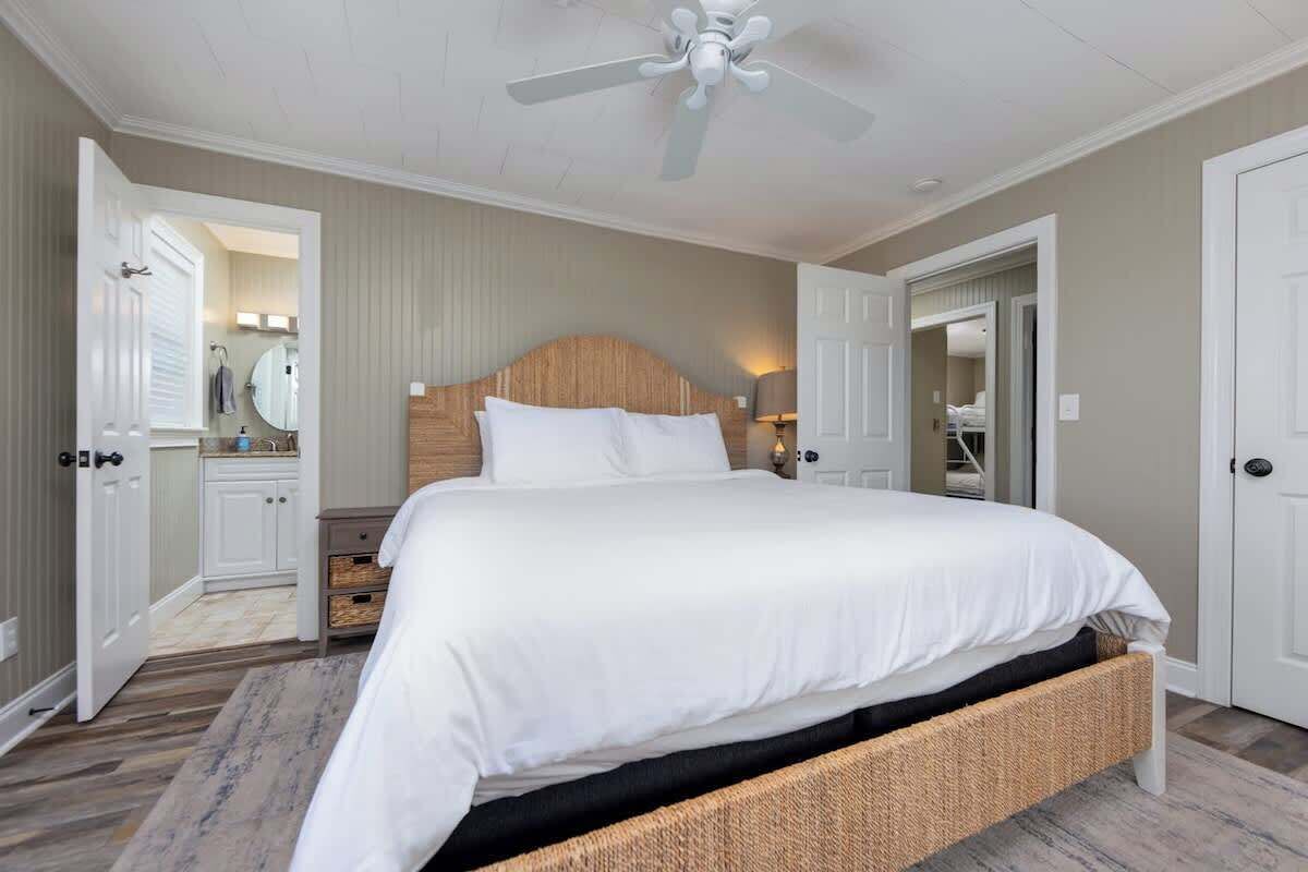 A bedroom with a large bed, a ceiling fan, and a wooden headboard.