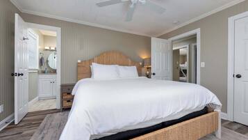 A bedroom with a large bed, a ceiling fan, and a wooden headboard.
