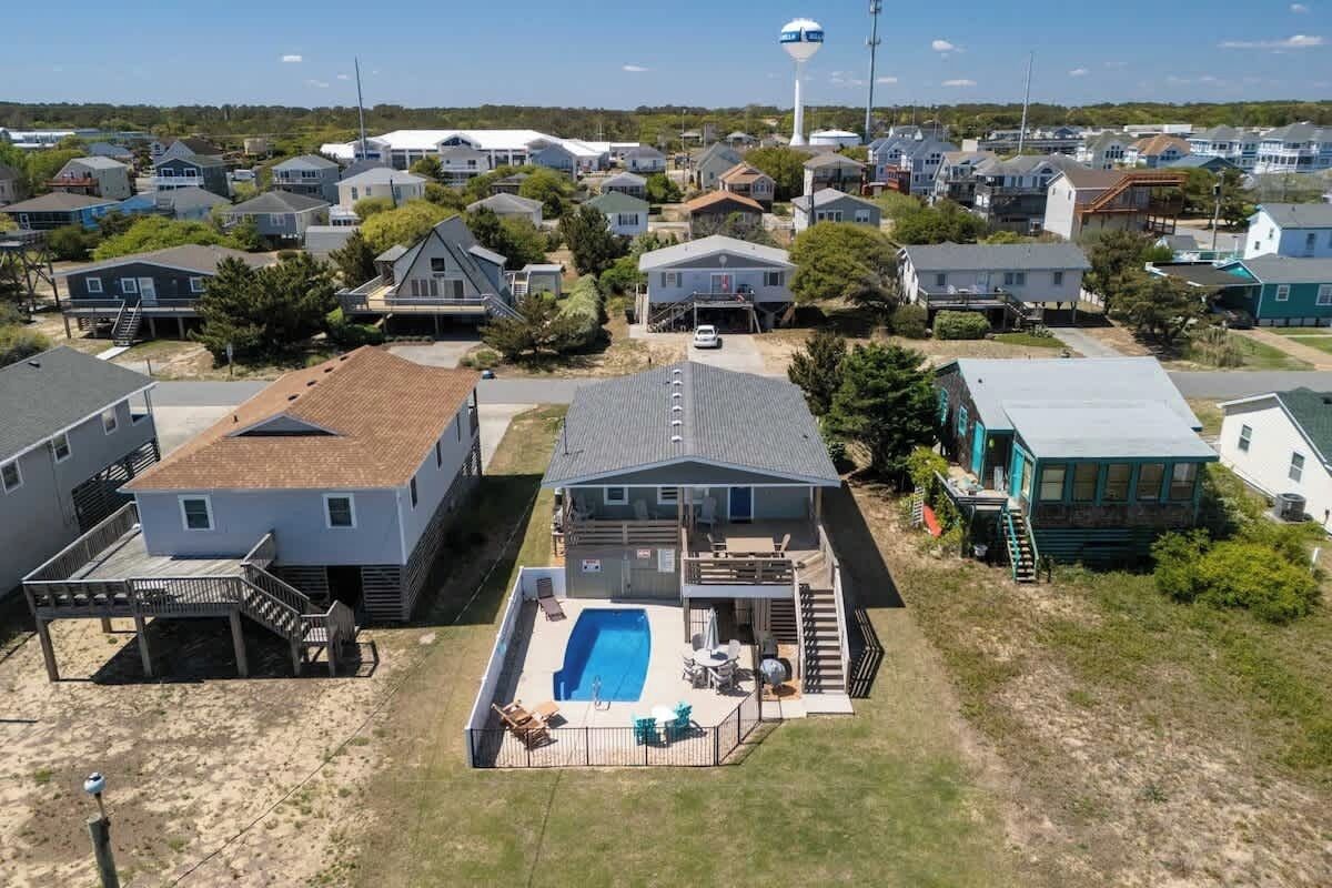 A residential area with a house featuring a swimming pool, a covered patio, and a small deck.