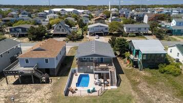 A residential area with a house featuring a swimming pool, a covered patio, and a small deck.