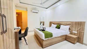 A modern bedroom with a wooden bed, bedside tables, a desk, and a chair. - Sky Hotel (Gurugram)