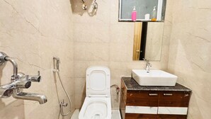 A bathroom with a toilet, sink, and shower. - Sky Hotel (Gurugram)