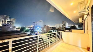 A balcony with a view of a cityscape at night. - Sky Hotel (Gurugram)