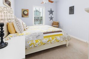 Ein Schlafzimmer mit Bett, Fenster, Stuhl und Wandgestaltungen.