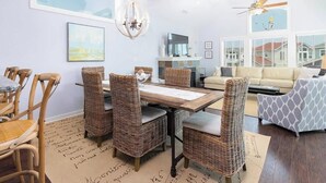 A living room with a dining area, wicker furniture, a fireplace, and a view of the outside.