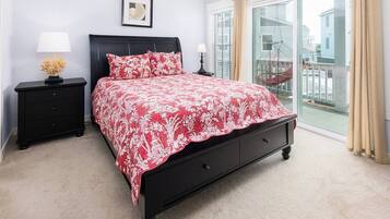 A bedroom with a bed, nightstands, a window with a view, and a door leading to a balcony.