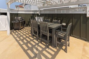 An outdoor patio with a table and chairs, a grill, and a covered area with a ceiling fan. - Dog Friendly Gorgeous Corolla Home Pool & Hot Tub (Corolla)