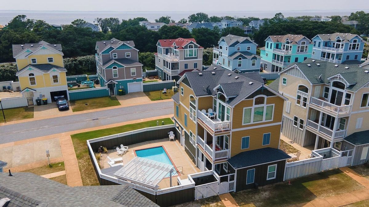Et boligområde med flere toetagers huse, en swimmingpool og en vej.