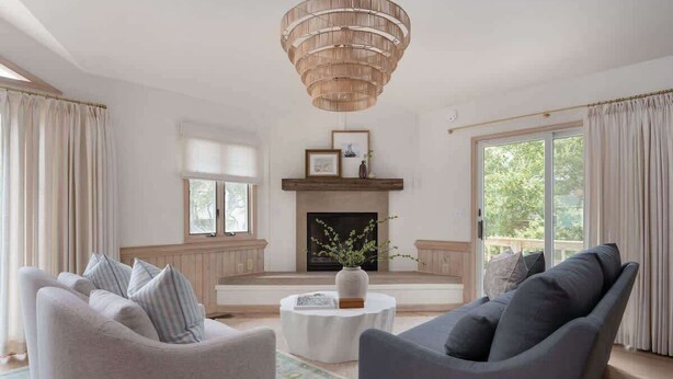 A living room with a fireplace, two sofas, a coffee table, and a chandelier.