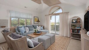 A spacious living room with a ceiling fan, a sofa set, a coffee table, and a bookshelf.
