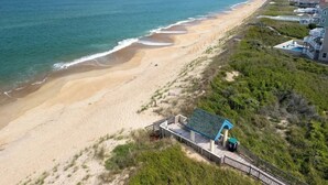 A coastal property with a beach view, a wooden boardwalk, and a small structure with a blue roof.