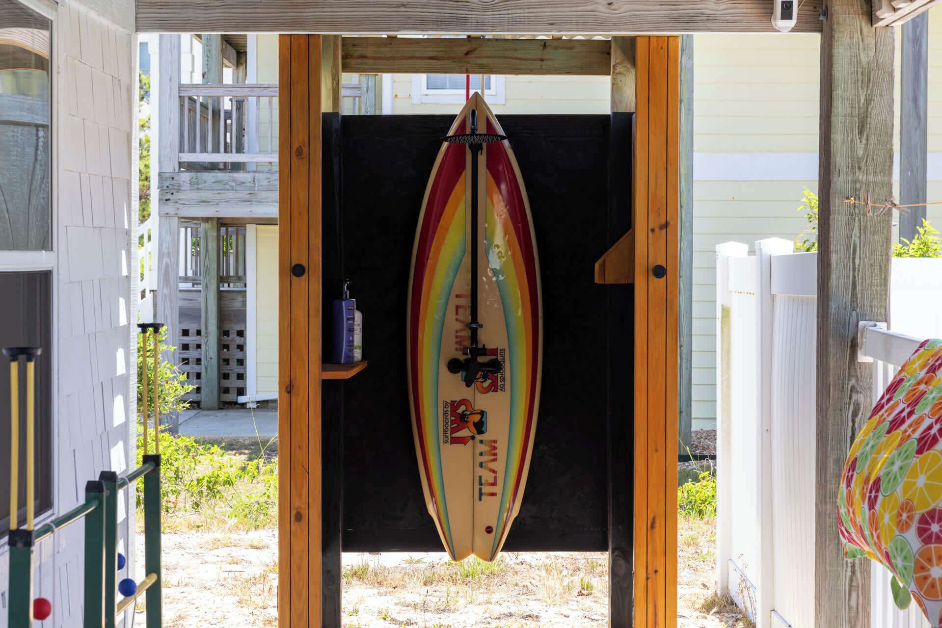 Una tavola da surf appesa a una struttura in legno, con un recinto bianco sullo sfondo.
