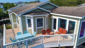Une maison à deux étages dotée d’une terrasse, d’un espace salon extérieur et d’un patio couvert.