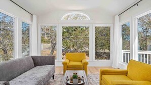 Une pièce baignée de lumière, avec un canapé gris, un fauteuil jaune et une table basse.