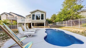 Il s’agit d’une propriété résidentielle dotée d’une piscine, de chaises longues et d’une maison à deux étages.