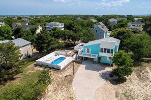 A residential area with houses, a swimming pool, and a large blue building. - Saltwater Pool | Hot Tub | Town of Duck (Duck)