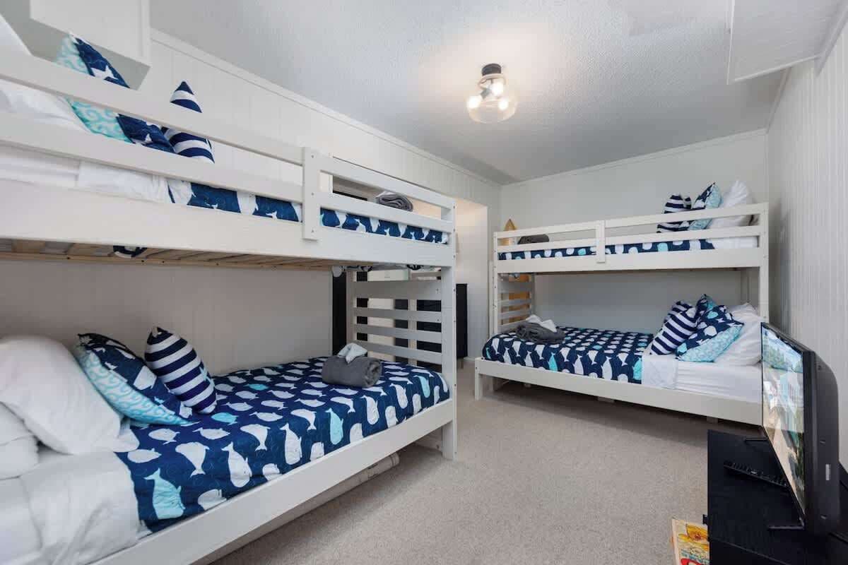 Een slaapkamer met stapelbedden, witte leuningen en beddengoed met een blauw patroon.