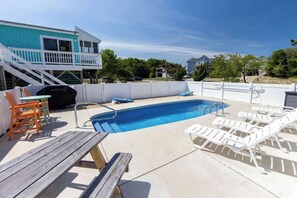 A backyard with a swimming pool, wooden deck, and outdoor furniture. - Saltwater Pool | Hot Tub | Town of Duck (Duck)
