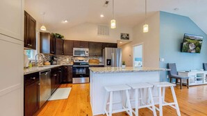 Une cuisine moderne avec des meubles en bois foncé, des appareils électroménagers en acier inoxydable et un grand îlot central doté de tabourets de bar.