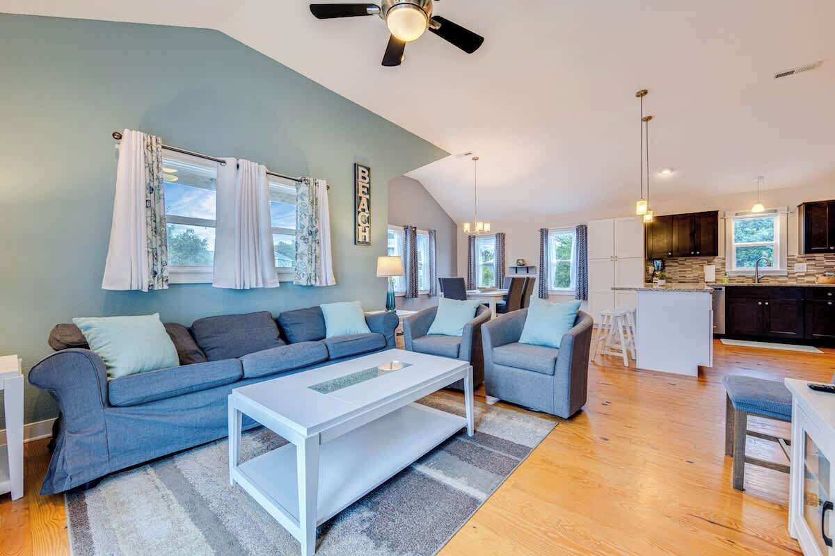 A modern living room with a grey sofa, a white coffee table, and a ceiling fan.