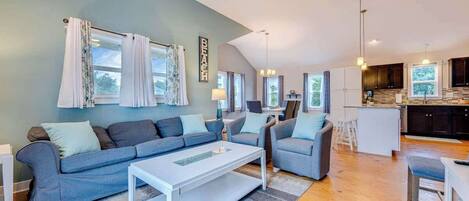 A modern living room with a grey sofa, a white coffee table, and a ceiling fan.