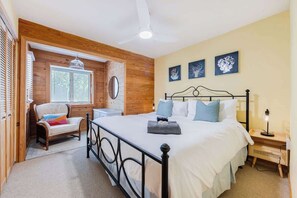 A bedroom with a bed, a chair, a bedside table, and a ceiling fan. - Pool, Hot Tub, Quick Walk to the Beach, EV Charger (Corolla)