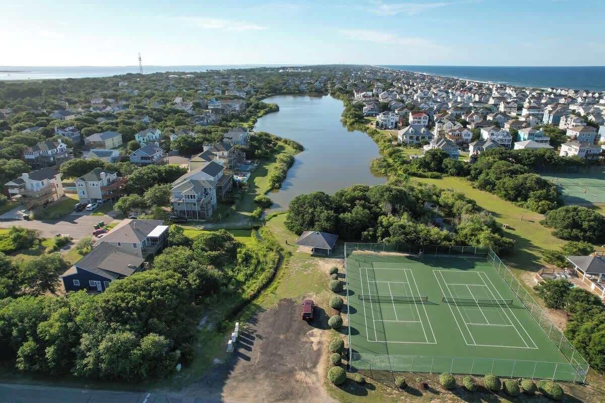 Vista aérea de um bairro residencial com casas, quadra de tênis e um rio.